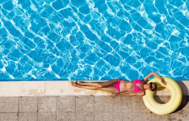 Çekici kadın kauçuk halka üzerinde döşeme ve yüzme havuzu rahatlatıcı pembe bikini