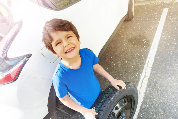 歳の少年 スペアタイヤと車の横に立っている笑顔とカメラ目線の上面の肖像画 — ストック写真