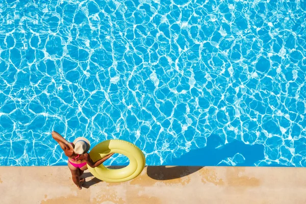 プールサイドに立って黄色のインフレータブル リングを押し コピー スペースで水面を見て麦わらのスリムな女性 — ストック写真