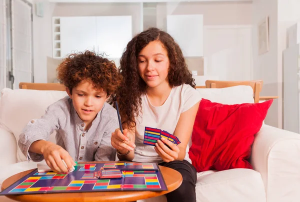 代の少年と一緒に自宅のテーブル ゲームをプレイ女の子の肖像画 — ストック写真