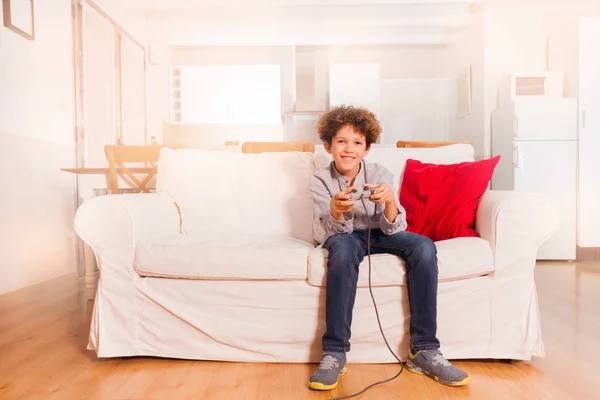 坐在沙发上 放学后玩电子游戏的快乐青春期男孩肖像 — 图库照片