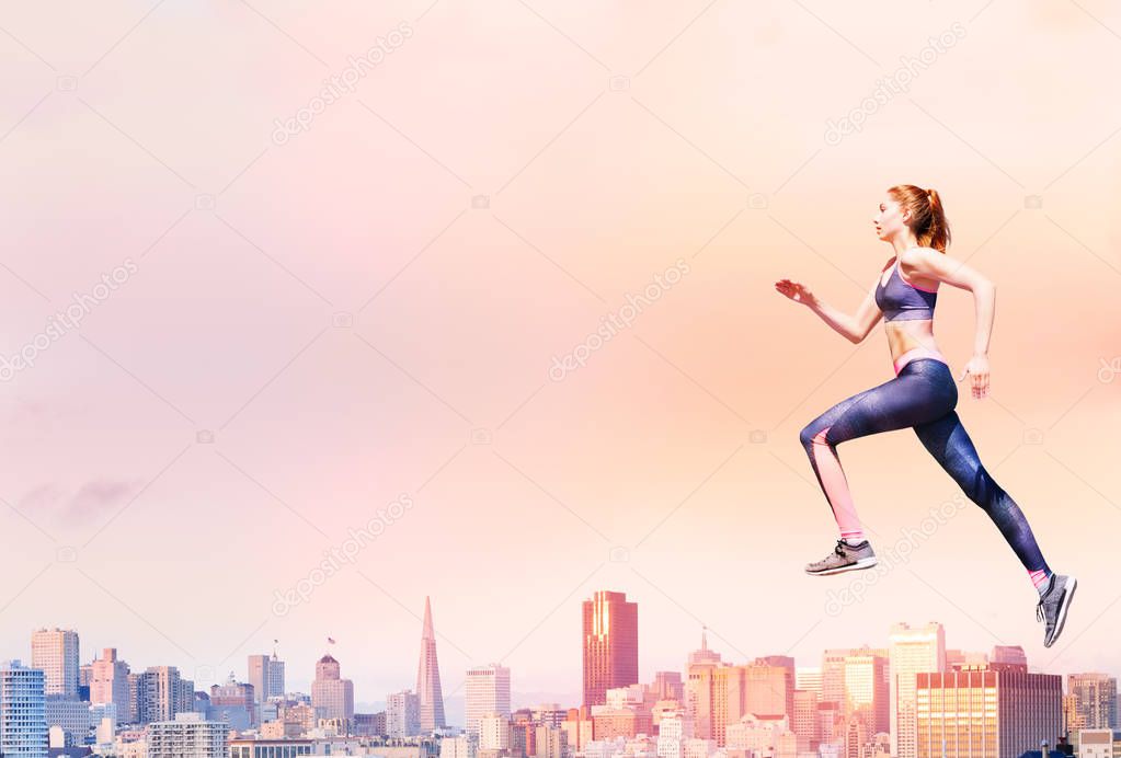 Conceptual dynamic shot of fit girl wearing sports bra and leggings running with San Francisco skyline on the background