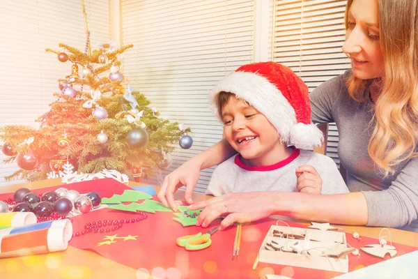 与她的儿子在家里做圣诞装饰品的快乐年轻女子肖像 — 图库照片