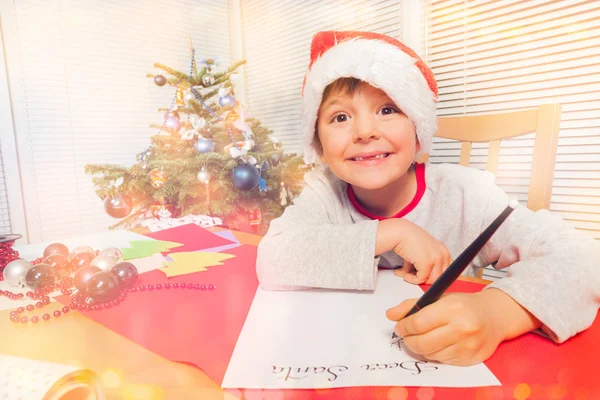 Retrato Menino Seis Anos Chapéu Papai Noel Sentado Mesa Escrevendo — Fotografia de Stock