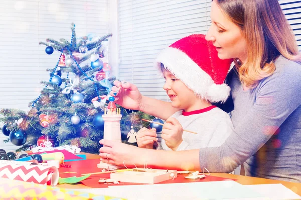 幸福的母亲和男孩的肖像装饰木制玩具坐在圣诞树旁 — 图库照片