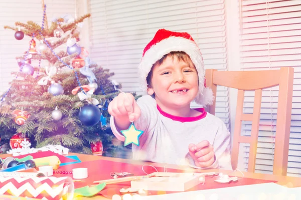 Fröhlicher Vorschulkind Mit Weihnachtsmütze Sitzt Schreibtisch Neben Dem Weihnachtsbaum Und — Stockfoto