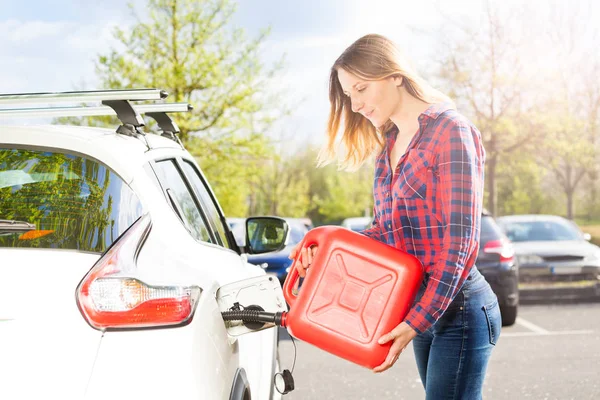 有吸引力的年轻妇女的侧面图片用红色塑料可以在外面的停车处装满汽车油箱 — 图库照片