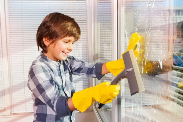 戴着海绵和玻璃雨刷的防护手套清洁窗户的小男孩肖像 — 图库照片