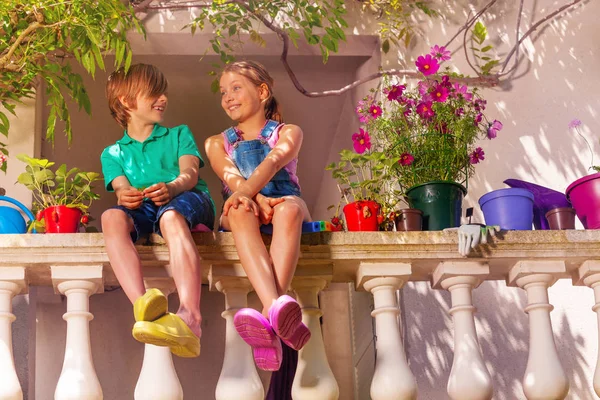 幸せのプレティーンの少年と鉢植えの花の中でテラスの手すりに座っている女の子のローアングル ショット — ストック写真