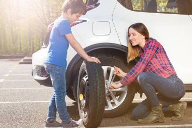 Yedi yaşında çocuk annesi dışında yer otopark, bir tekerlek değiştirmek için yardım portresi