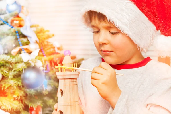 特写肖像的学龄前男孩 小圣诞老人的助手 装饰木制玩具与黄色油漆 — 图库照片