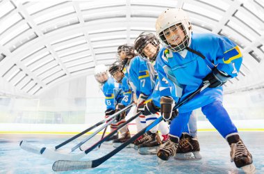 Mutlu çocuk portresi, hokey oyuncuları birbiri ardına ayakta, sopa ile buz pateni pisti