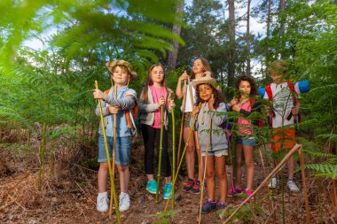 Grup çocuk ayakta tutan el yapımı hiking Polonyalılar yele bambu sopalarla yürüyüş sırasında dinlenme ormandaki