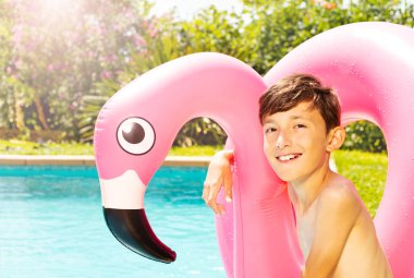 Mutlu genç çocuk yüzme havuzu kenarında dev pembe yüzmek yüzükle oturma portre