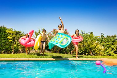 Mutlu gençler yüzme araçlar, koşma ve açık hava havuz partisi sırasında suya atlama ile portresi