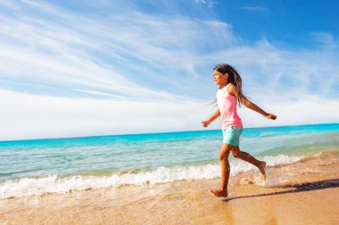 Yan görünümü karşı tropikal deniz manzarası güneşli gün çalışan Sportif Asyalı Kız portresi