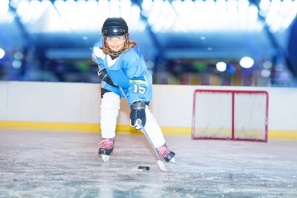 Portrait of smiling girl, ice hockey player, passing the puck during game on the rink
