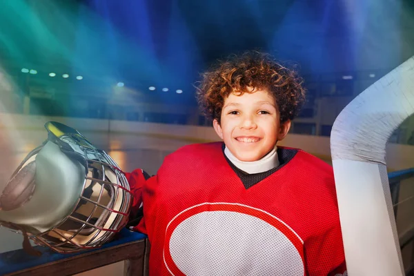 赤で統一 アイス スケート リンクの掲示板の隣に立って笑顔とカメラ目線での若いホッケー選手のクローズ アップの肖像画 — ストック写真