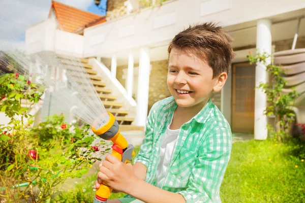 七岁男孩的肖像在后院浇水时玩洒水水喷头 — 图库照片