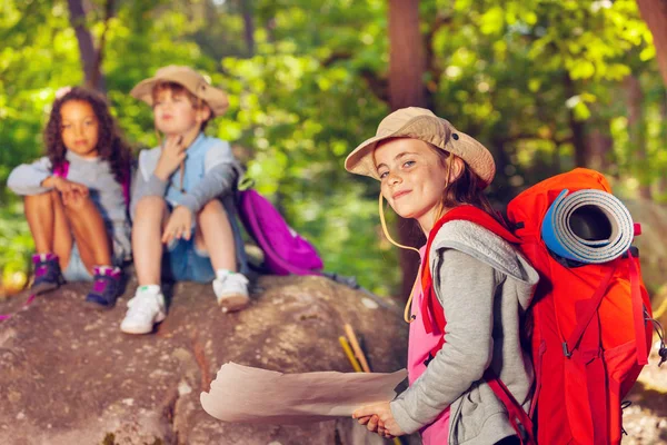 Girl with treasure map in the forest wearing backpack during navigation activity in summer camp