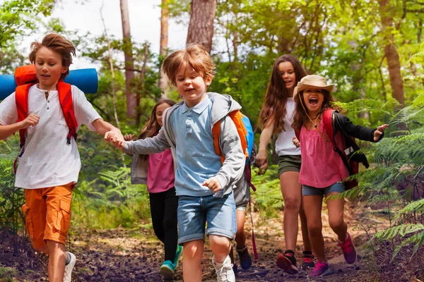 儿童男孩和女孩的画像在森林里一起奔跑在学校自然露营之旅中牵手 — 图库照片