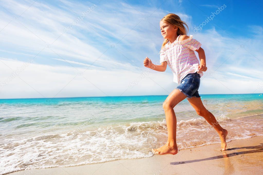Side view portrait of beautiful girl running along sandy beach in summer