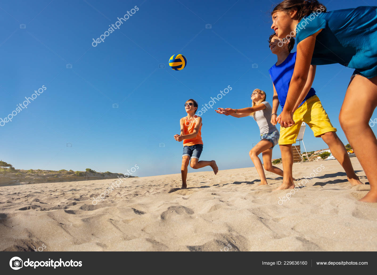 Garoto Joga Bola De Futebol Na Praia Arenosa. Pés Descalços De