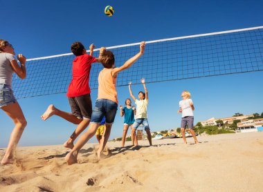 Genç erkek ve kız sahilde voleybol oynarken büyük grup