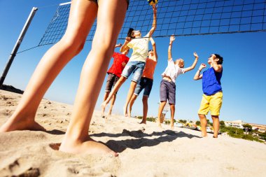 Genç erkek ve kız yaz aylarında plaj voleybolu oynarken aşağılardan görünümünü