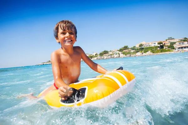 海辺で夏を過ごすスイミング マットレスの上の波に乗って陽気な少年の肖像画 — ストック写真