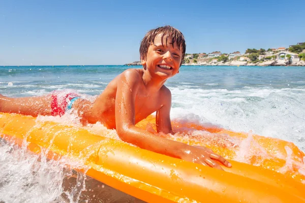 海辺で夏休みを過ごす波に乗って大きなスイミング マットレス かわいい男の子の肖像画 — ストック写真