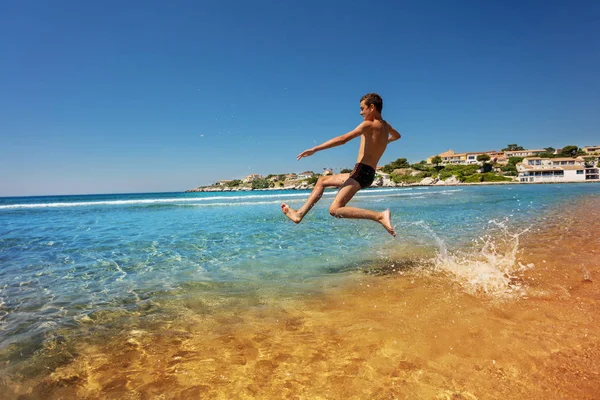 海辺で夏を過ごす 代の少年を水に飛び込む像側ビュー — ストック写真