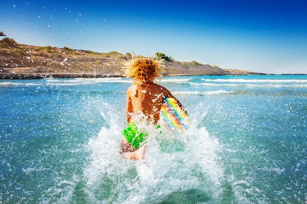波に乗る準備ボディー ボードと海に走っているアクティブな 代少年の背面図 — ストック写真