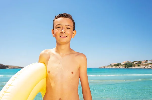 Portret Uśmiechnięty Chłopiec Stojący Żółtym Pierścieniem Nadmuchiwane Nad Brzegiem Morza — Zdjęcie stockowe