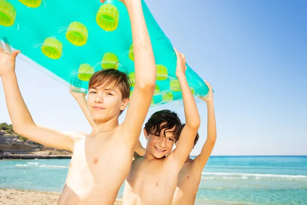 海水泳後彼らの頭上の大きな空気マットレスを運ぶ つの十代の少年たちの肖像 — ストック写真