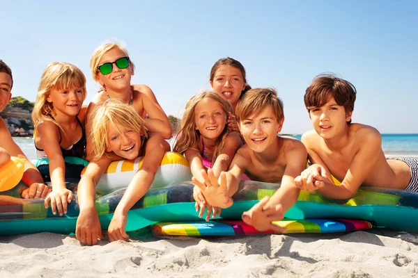 大批男孩和女孩 笑着的朋友 躺在游泳设备堆上 在海滩上晒太阳 — 图库照片