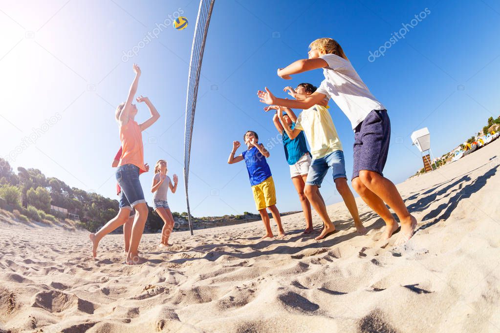 Low-angle shot of teenage boy serving the ball during beach volleyball match