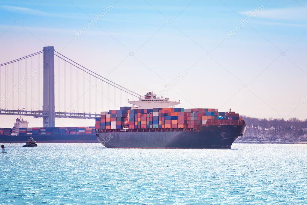 Tugboat towing the full loaded cargo ship from the maritime port