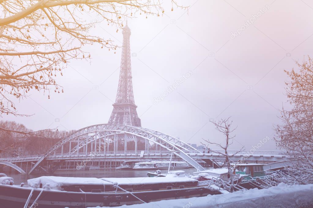 Winter landscape of the Seine river embankment with Debilly footbridge and the Eiffel tower on the background in snow, Paris, France