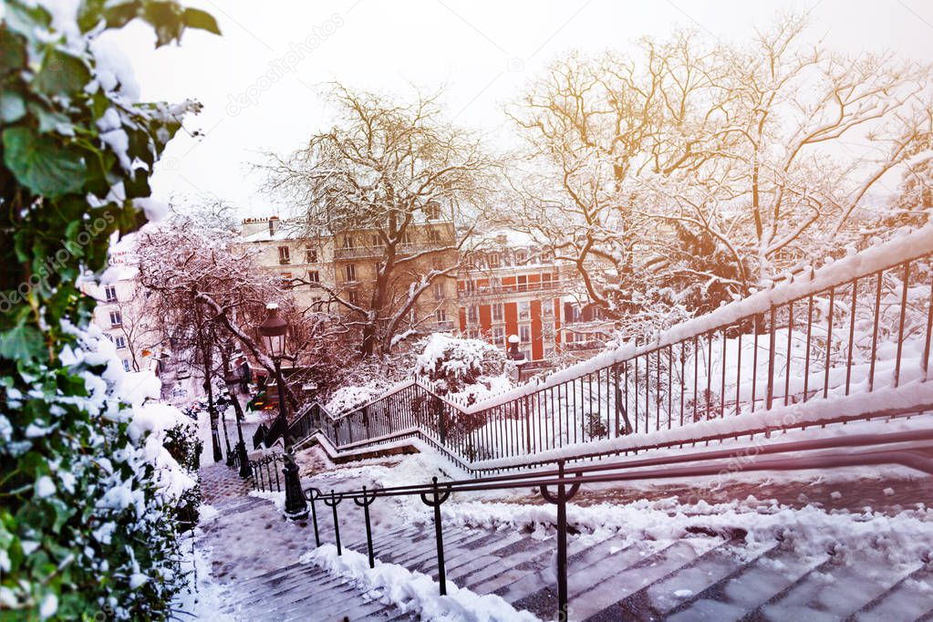Beautiful winter cityscape of Paris city with icy stairways, snow-covered trees and buildings after snowfall