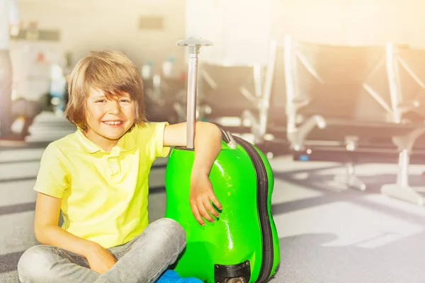 楽しんで 空港でスーツケースを持って座っている 休暇旅行に行く白人 歳男の子 — ストック写真