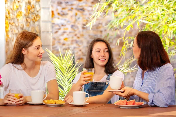 Mother and two daughters having breakfast outdoor — Stock Photo, Image