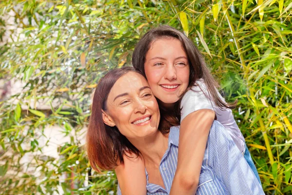 Happy teenage girl giving her mother back hug — Stock Photo, Image