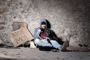 Clochard adam köpeğiyle sokakta oturan