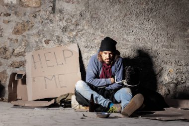 Homeless man sitting on the street with a dog clipart