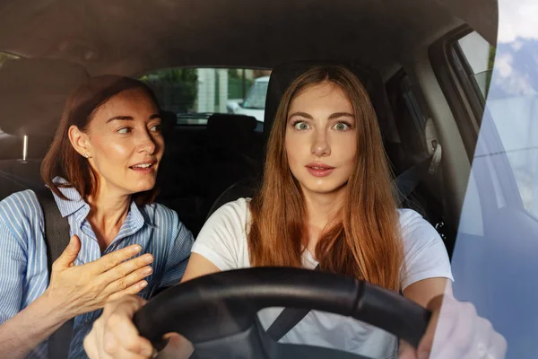 Menina surpresa com sua mãe dirigindo um carro — Fotografia de Stock