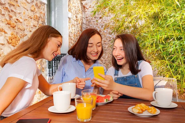 Menina tomando café da manhã em família e usando smartphone — Fotografia de Stock