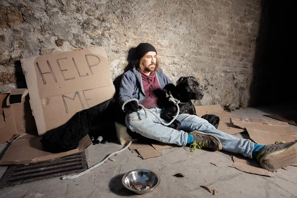 Tramp étreignant son chien assis sur le trottoir de la ville — Photo