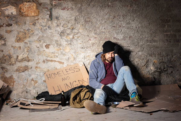 Unhappy man sitting on the floor with alms basket