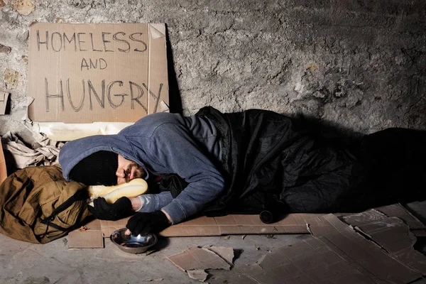 Homme sans foyer dormant dans la rue avec boîte d'aumônes — Photo